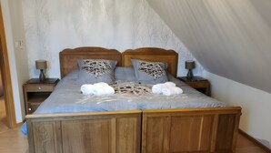 Ein hölzernes Bett mit blauer Bettdecke, zwei Nachttische mit Lampen und eine Wand mit Baummuster.