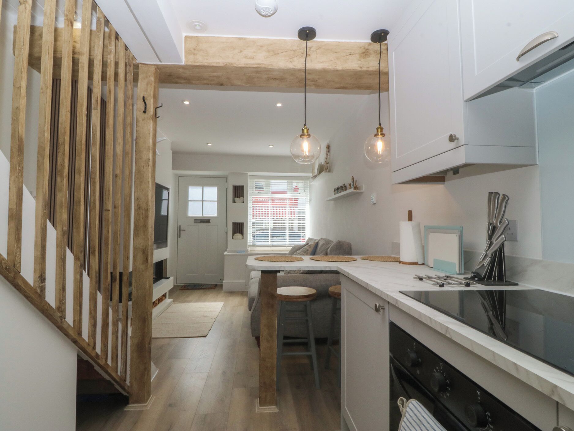 A modern kitchen with wooden beams, pendant lights, a central island, and a built-in oven.