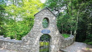 A stone structure with a plaque, a metal gate, and a stone pathway.