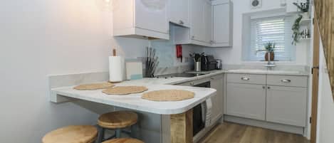 A modern kitchen with a central island, bar stools, and pendant lighting.