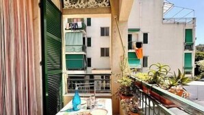 Un balcon avec une table, des chaises et des plantes en pot.