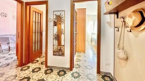 Un couloir avec un sol à motifs, des portes en bois, un miroir et un chapeau accroché au mur.