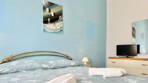 Une chambre à coucher avec un lit, une télévision, une lampe et un tableau au mur.