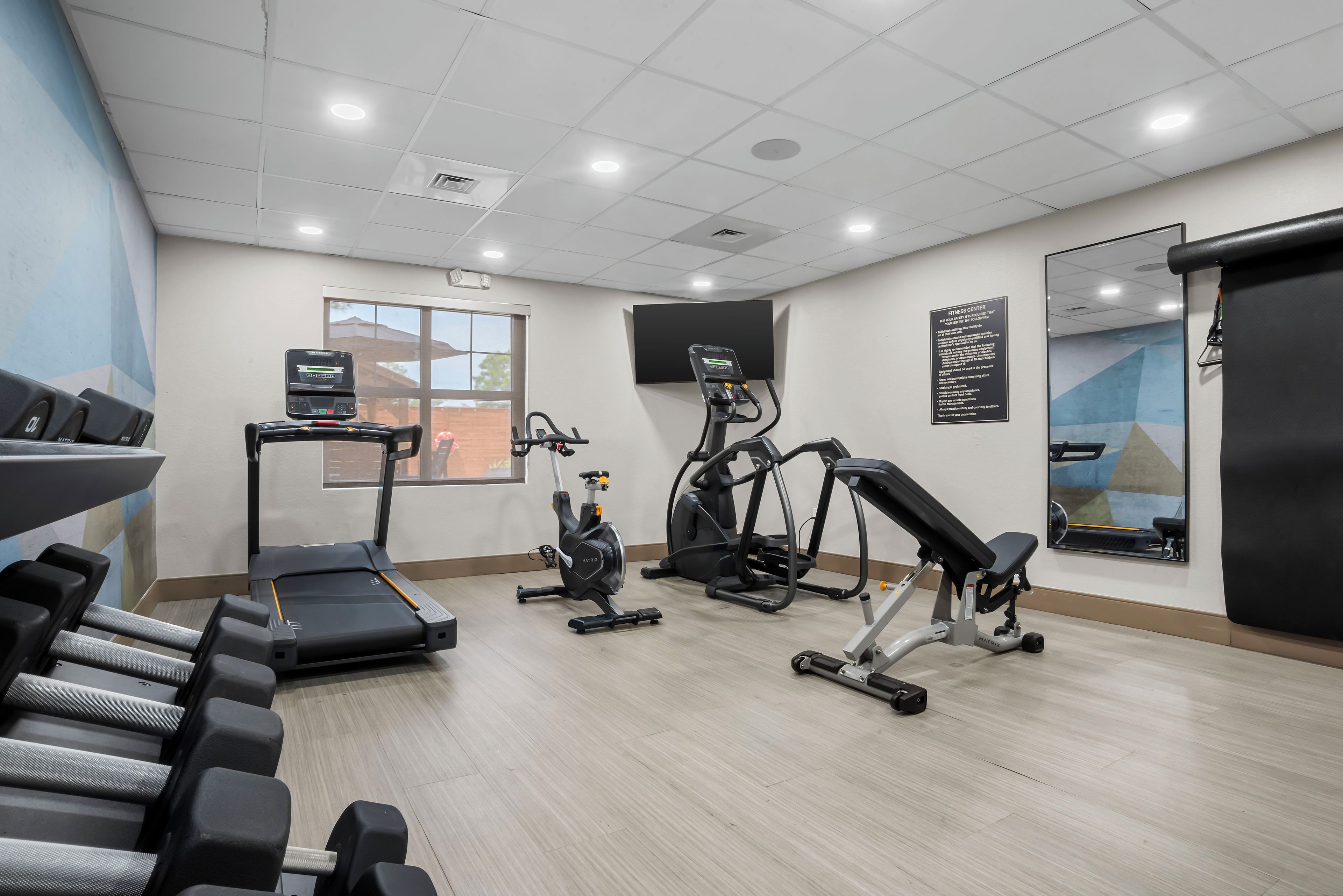 A fitness center with treadmills, an elliptical, and a bench.