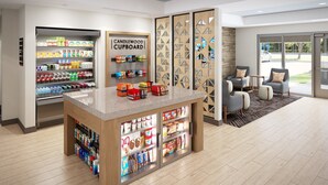 A modern kitchenette with a coffee machine, a refrigerator stocked with beverages, and a sign for a candlewood cupboard. - Candlewood Suites Panama City Beach Southeast By Ihg (Panama City Beach)
