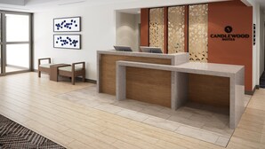 A reception desk with a modern design, two framed abstract artworks on the wall, and a 'CANDLEWOOD SUITES' sign. - Candlewood Suites Panama City Beach Southeast By Ihg (Panama City Beach)