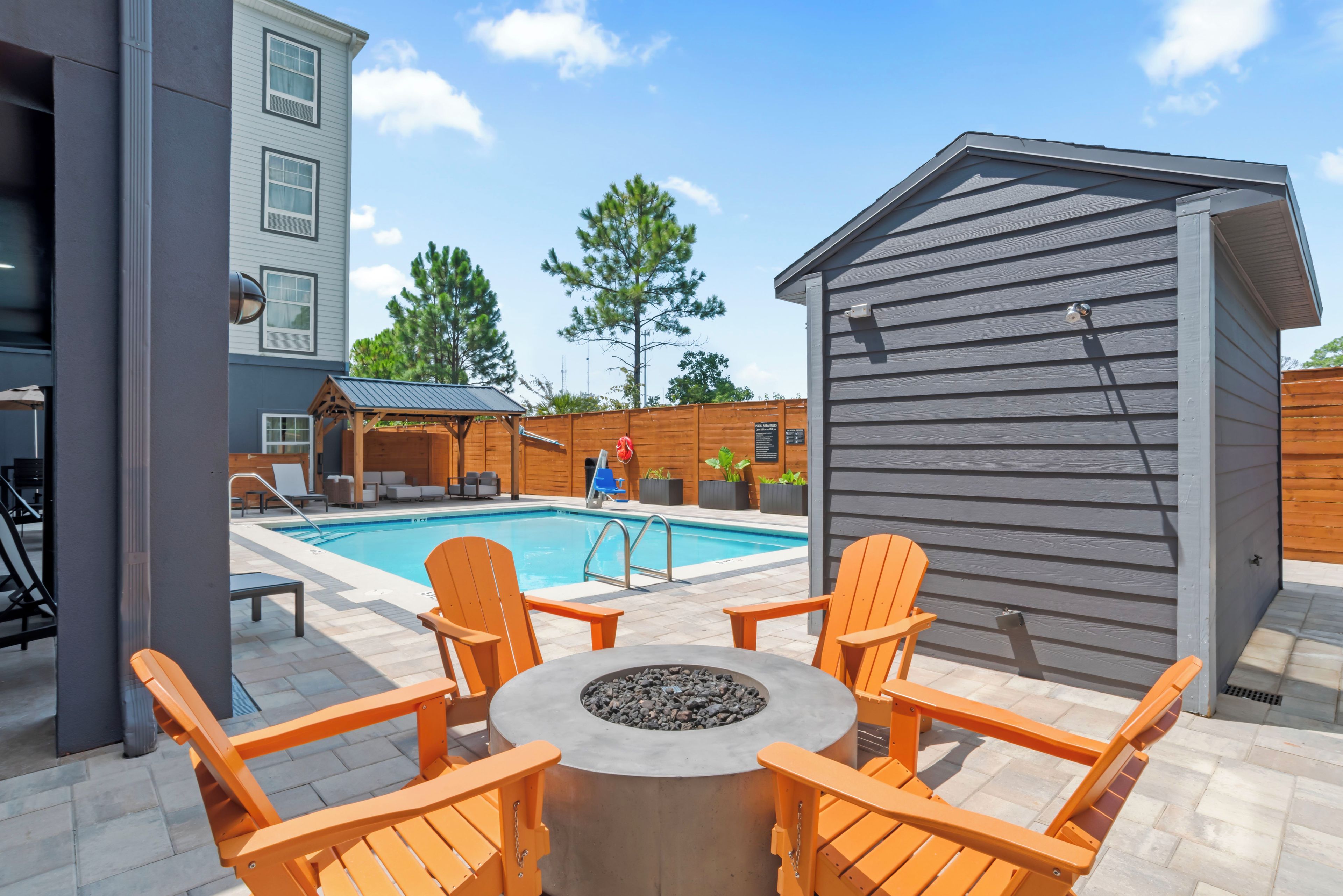 A pool area with a hot tub, lounge chairs, and a small wooden structure.