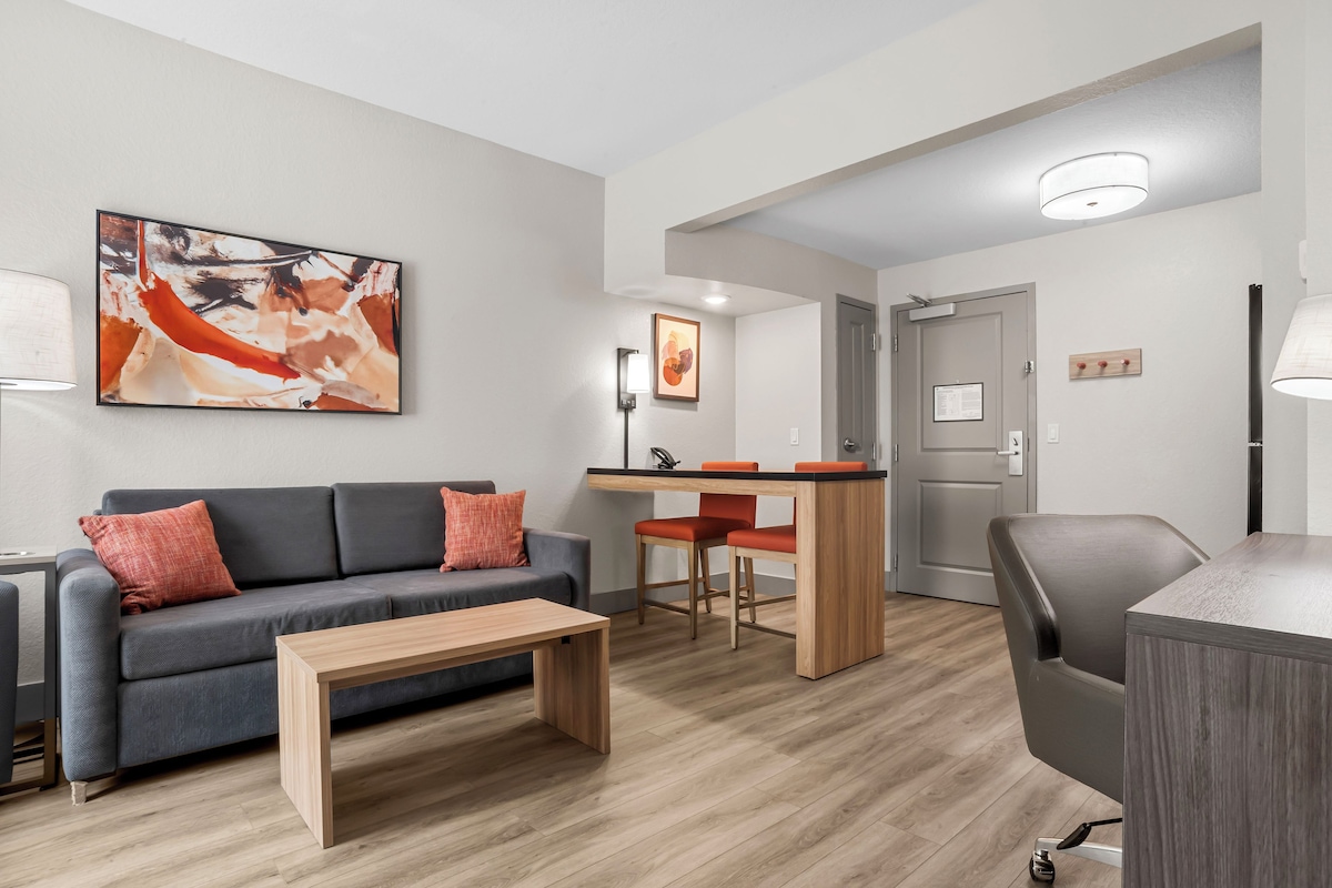 A modern living room with a sofa, a coffee table, and a dining area with a table and chairs.