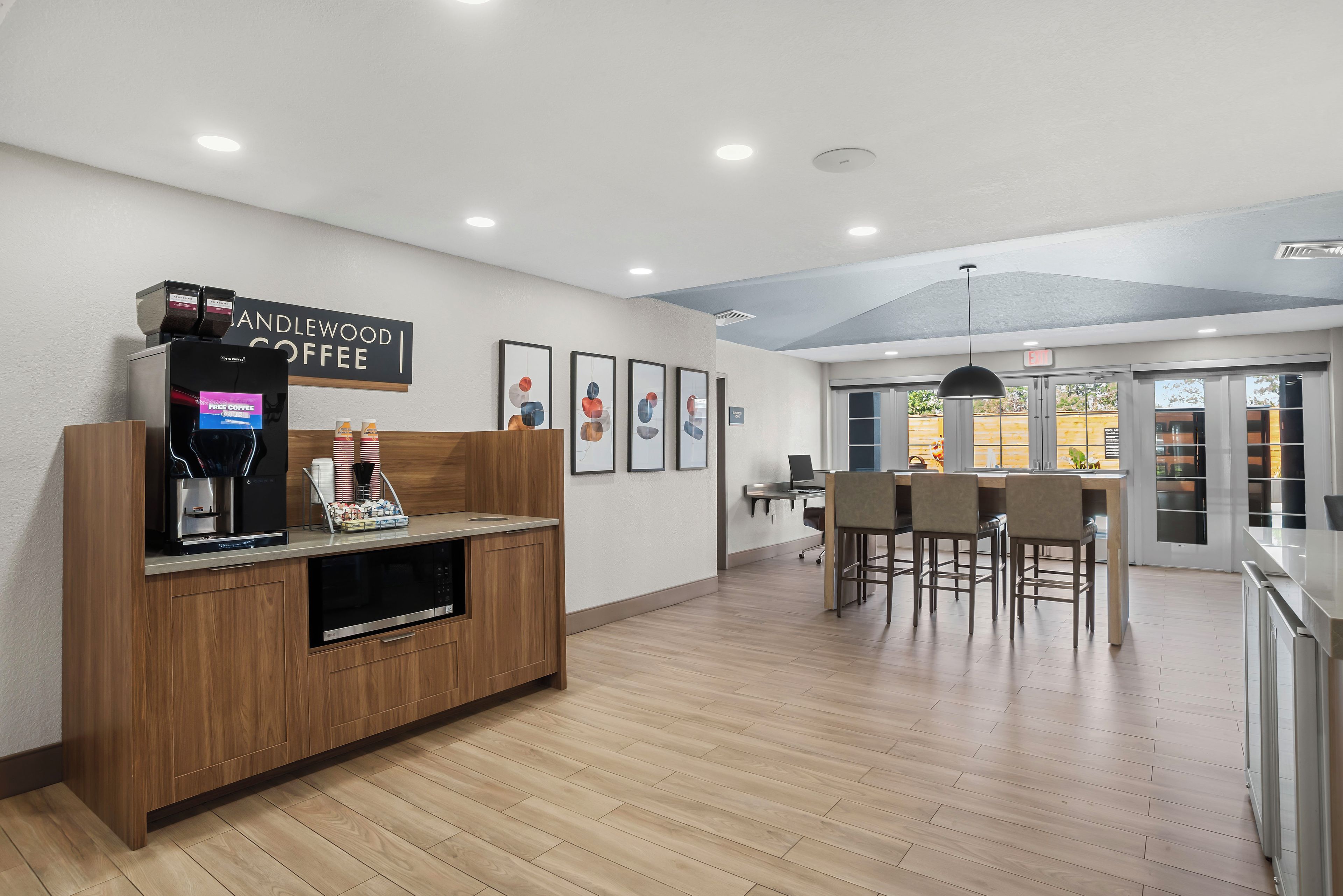 A modern coffee shop interior with a coffee machine, seating area, and artwork on the walls.