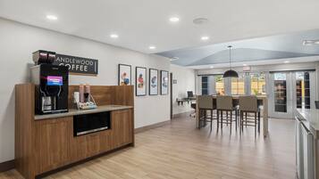 A modern coffee shop interior with a coffee machine, seating area, and artwork on the walls.