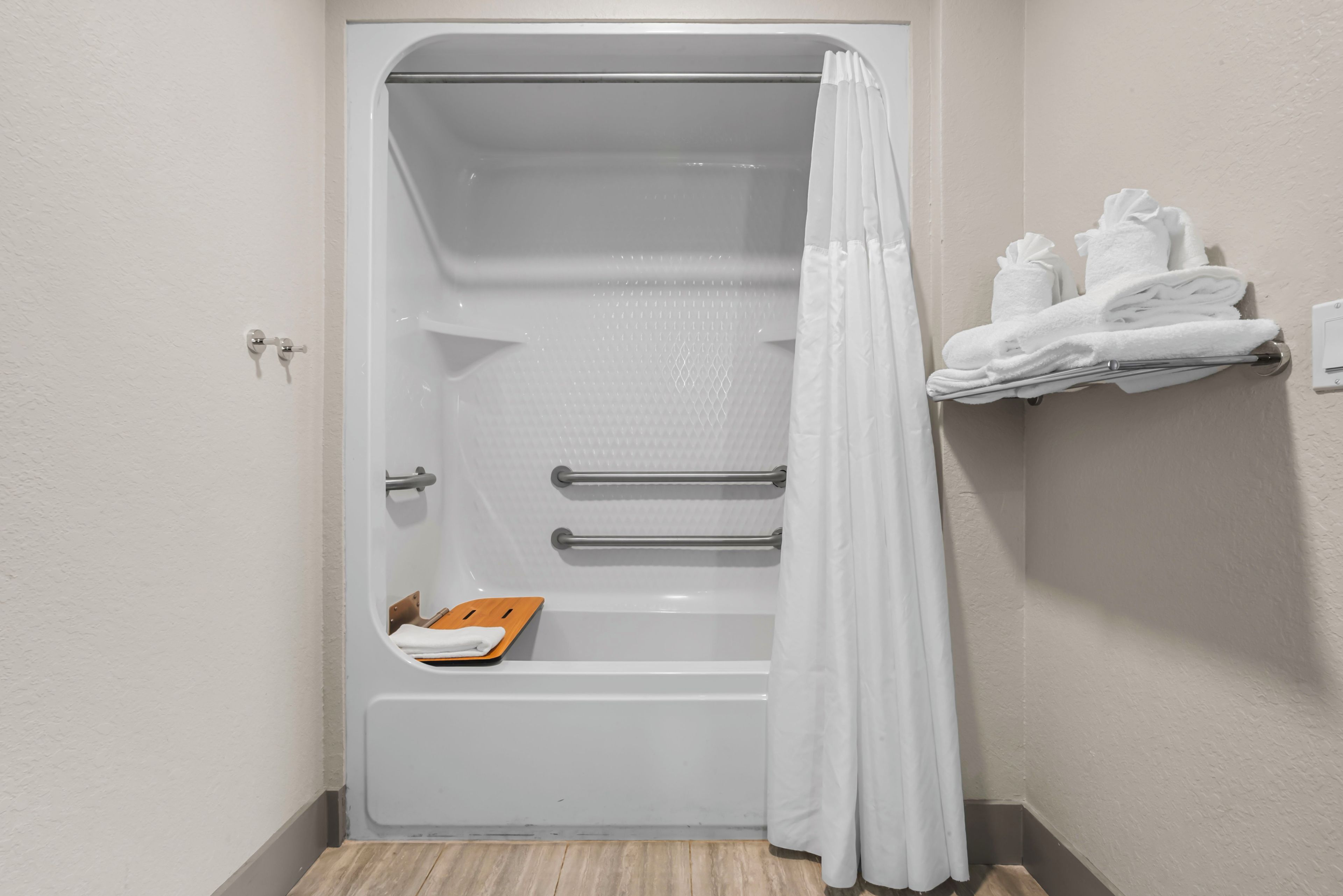 A bathroom with a bathtub, a shower curtain, and a towel rack with folded towels.
