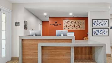Un mostrador de recepción con panel de madera, un letrero de Candlewood Suites y una pared con diseños geométricos.