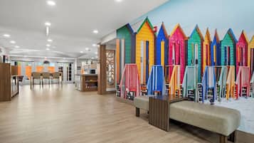 Un intérieur moderne avec un plancher en bois, un coin salon et une fresque colorée représentant des cabanes de plage.