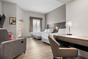 A hotel room with a bed, a desk, a chair, a lamp, and a painting on the wall.