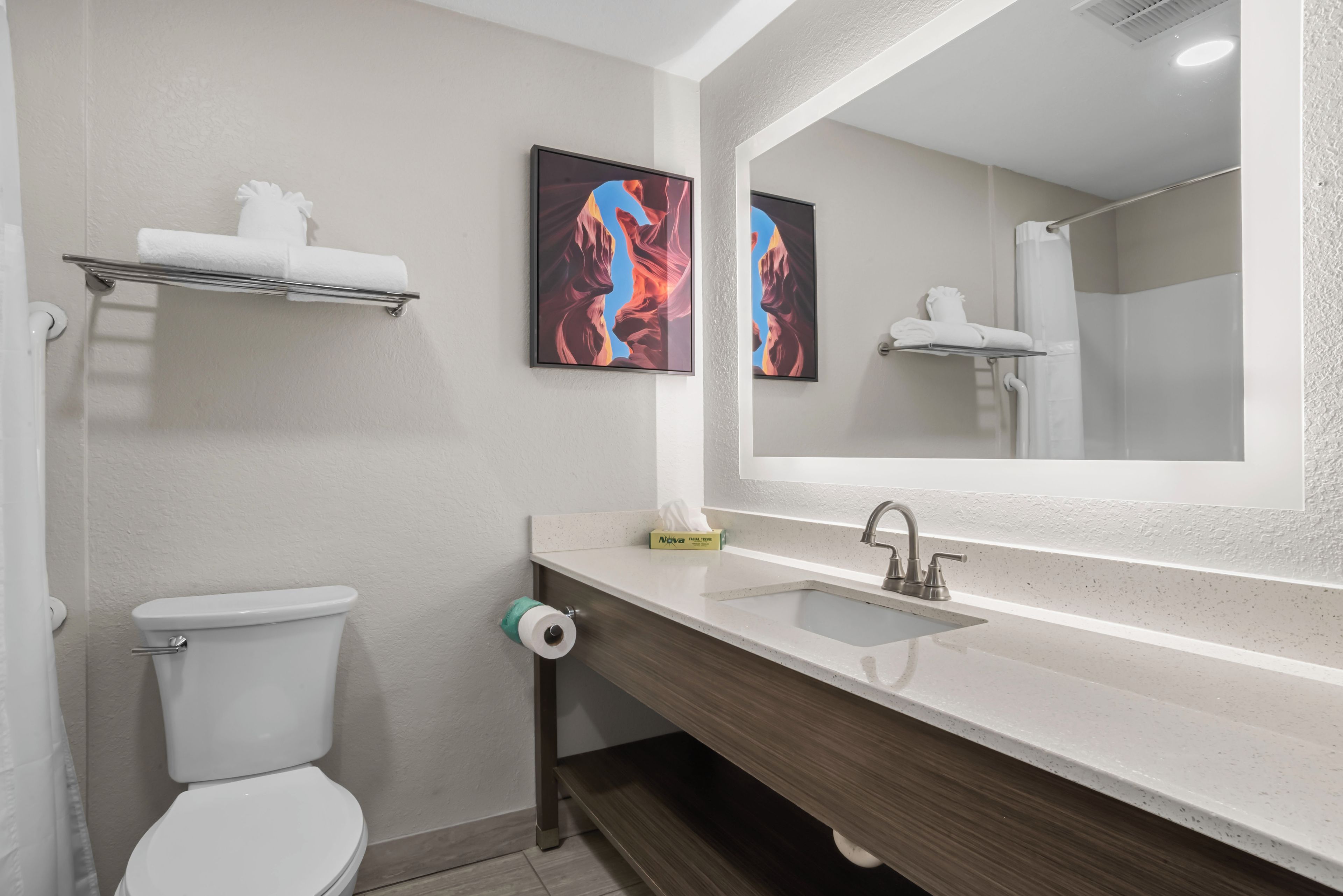 A modern bathroom with a toilet, sink, and mirror.