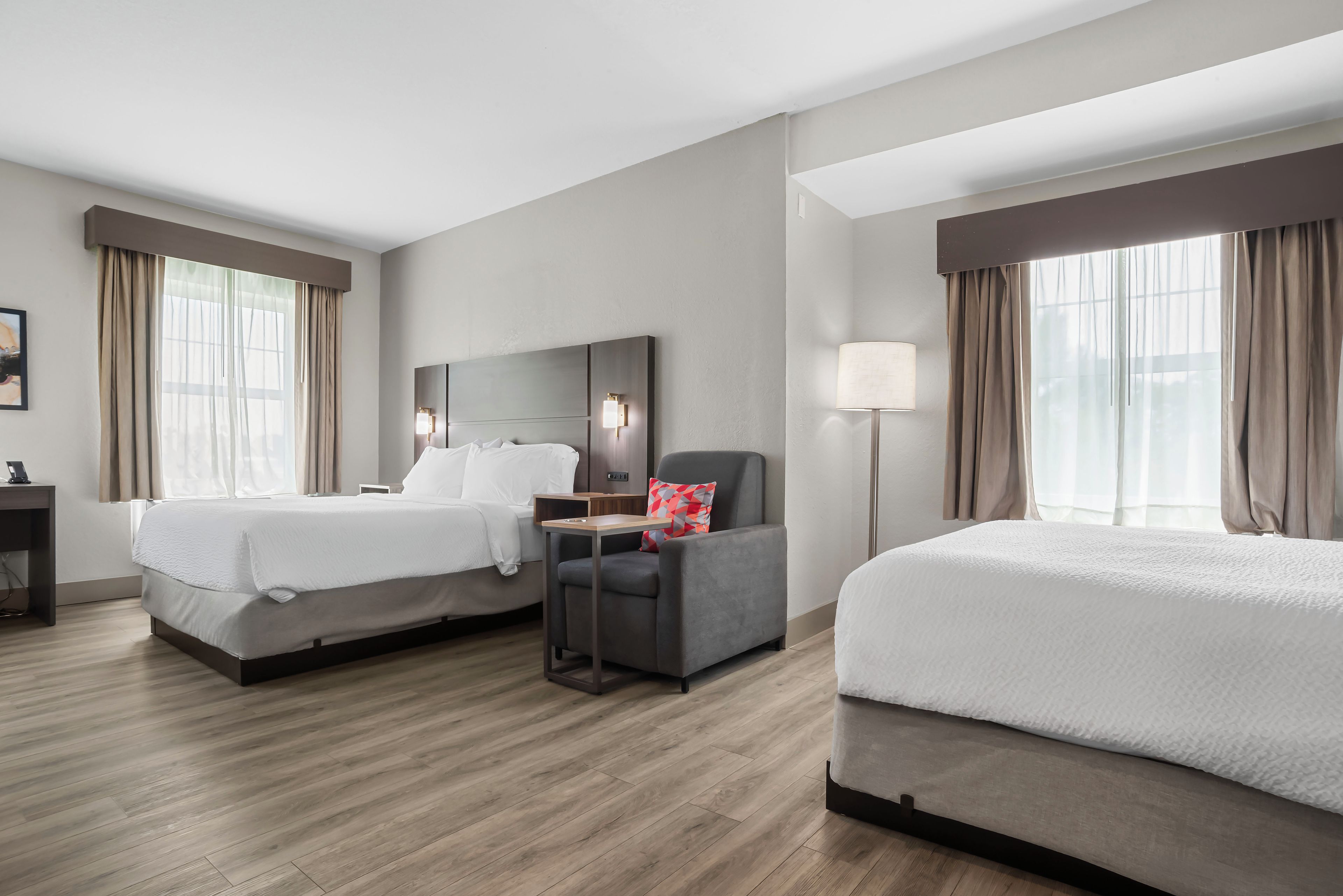 Una habitación de hotel con dos camas, un escritorio, una silla y una mesita de noche.