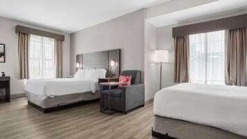 Una habitación de hotel con dos camas, un escritorio, una silla y una mesita de noche.