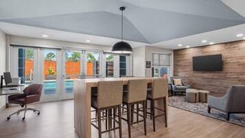 A modern interior with a bar area, seating, and a large TV on the wall.