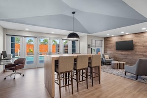 A modern interior with a bar area, seating, and a large TV on the wall.