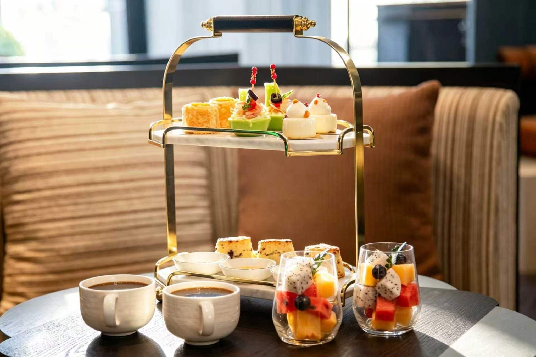 Una bandeja con pasteles variados y un vaso de ensalada de frutas sobre una mesa.
