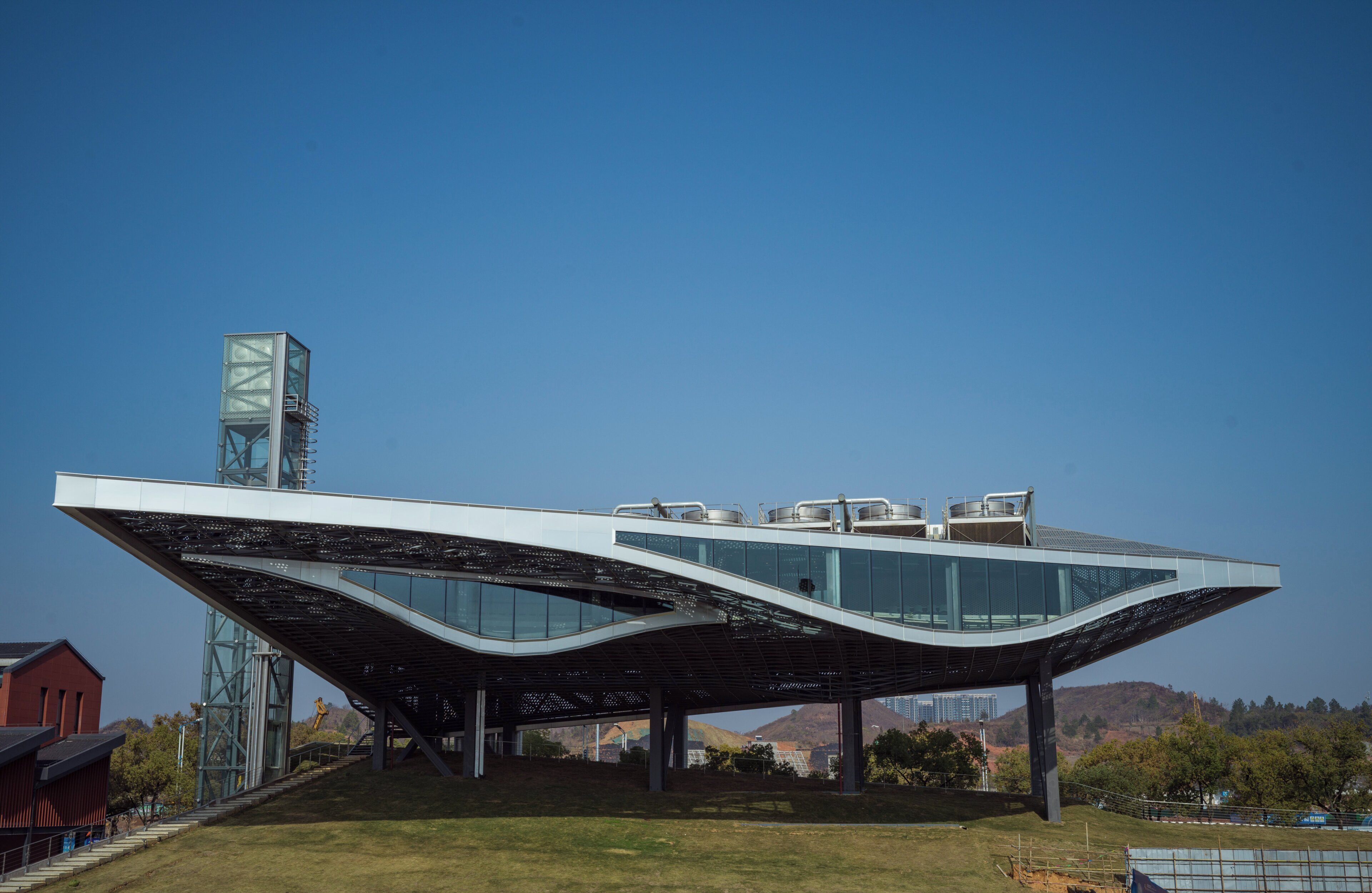 A modern building with a unique curved roof and a glass facade.