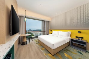 Une chambre d’hôtel moderne dotée d’un grand lit, d’une télévision à écran plat, d’un coin repas et offrant une vue sur la ville.