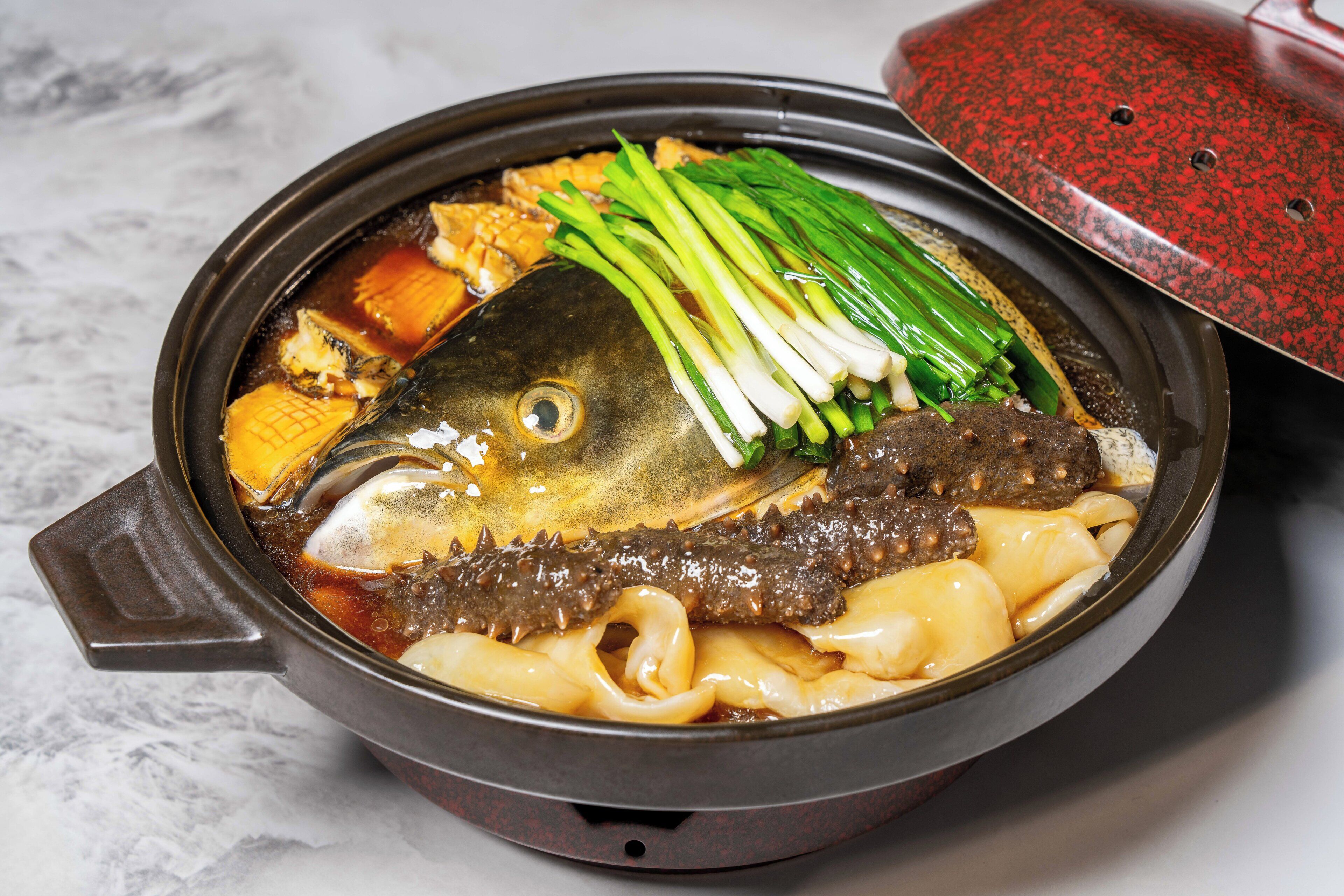 A bowl of soup with fish, noodles, and green onions.