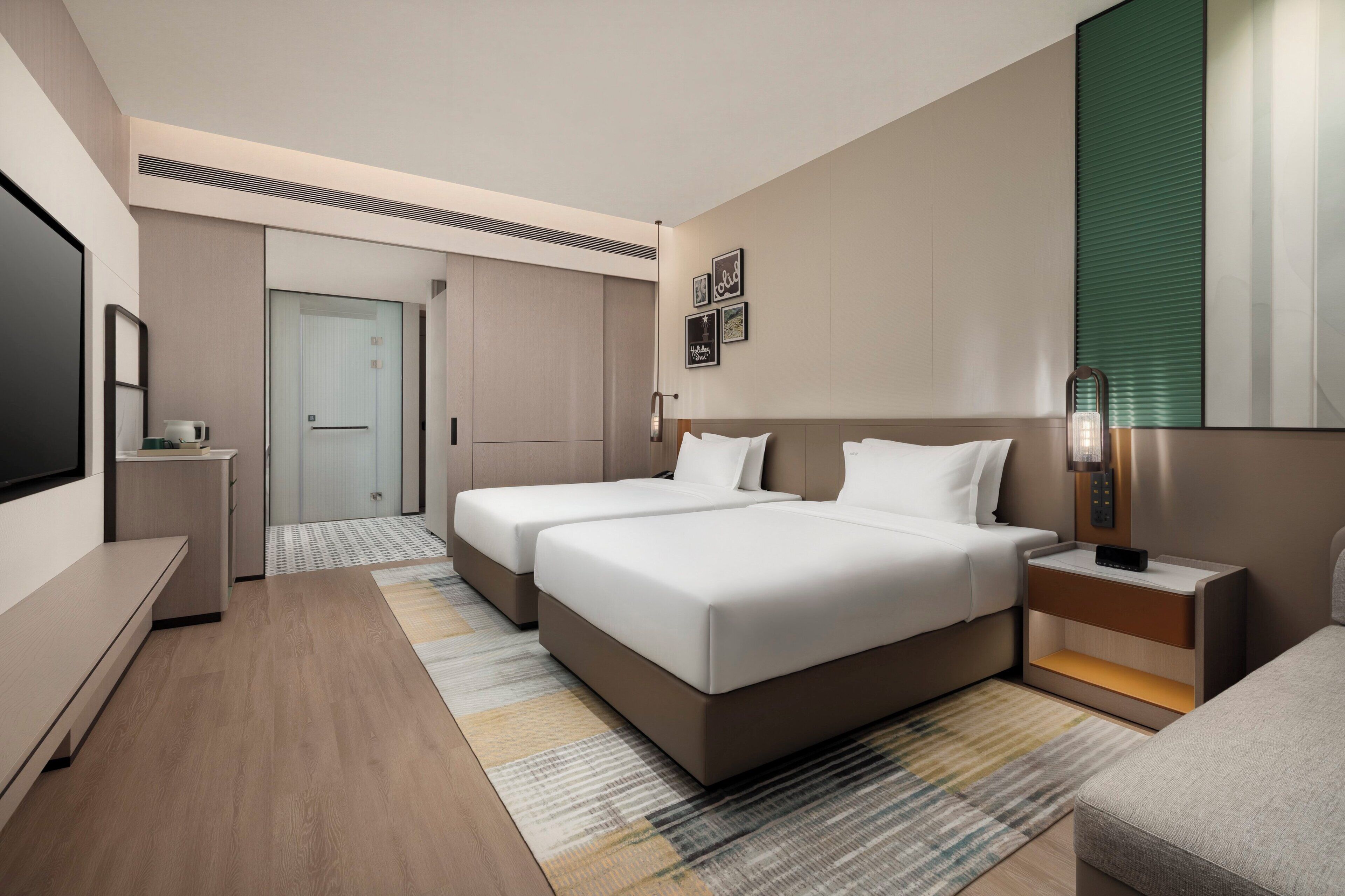 A modern hotel room with a large bed, bedside tables, a TV, and a door leading to a bathroom.