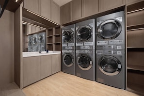 A modern laundry facility with six washing machines, a counter, and wooden cabinetry.