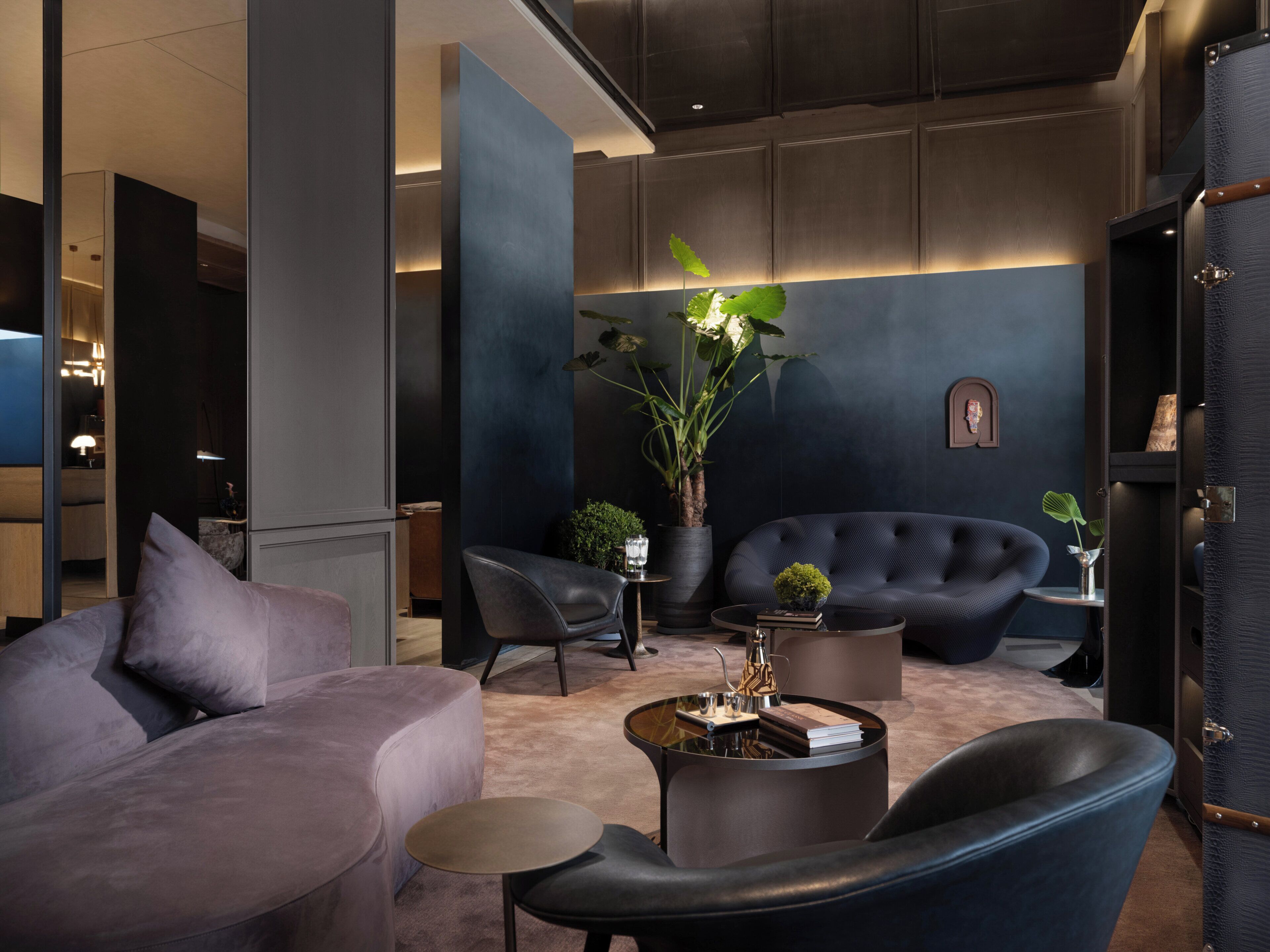 Een moderne zithoek met een bank, fauteuils, een salontafel en een potplant.