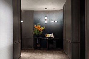 A modern interior with a dark wall, a wooden floor, a round table with a vase of flowers, and pendant lighting. - Holiday Inn Express Shanghai Jing An Xikang Road By Ihg (Shanghai)