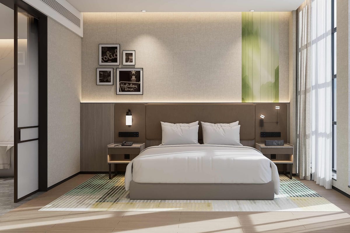 A modern hotel room with a large bed, bedside tables, a wall-mounted artwork, and a large window.