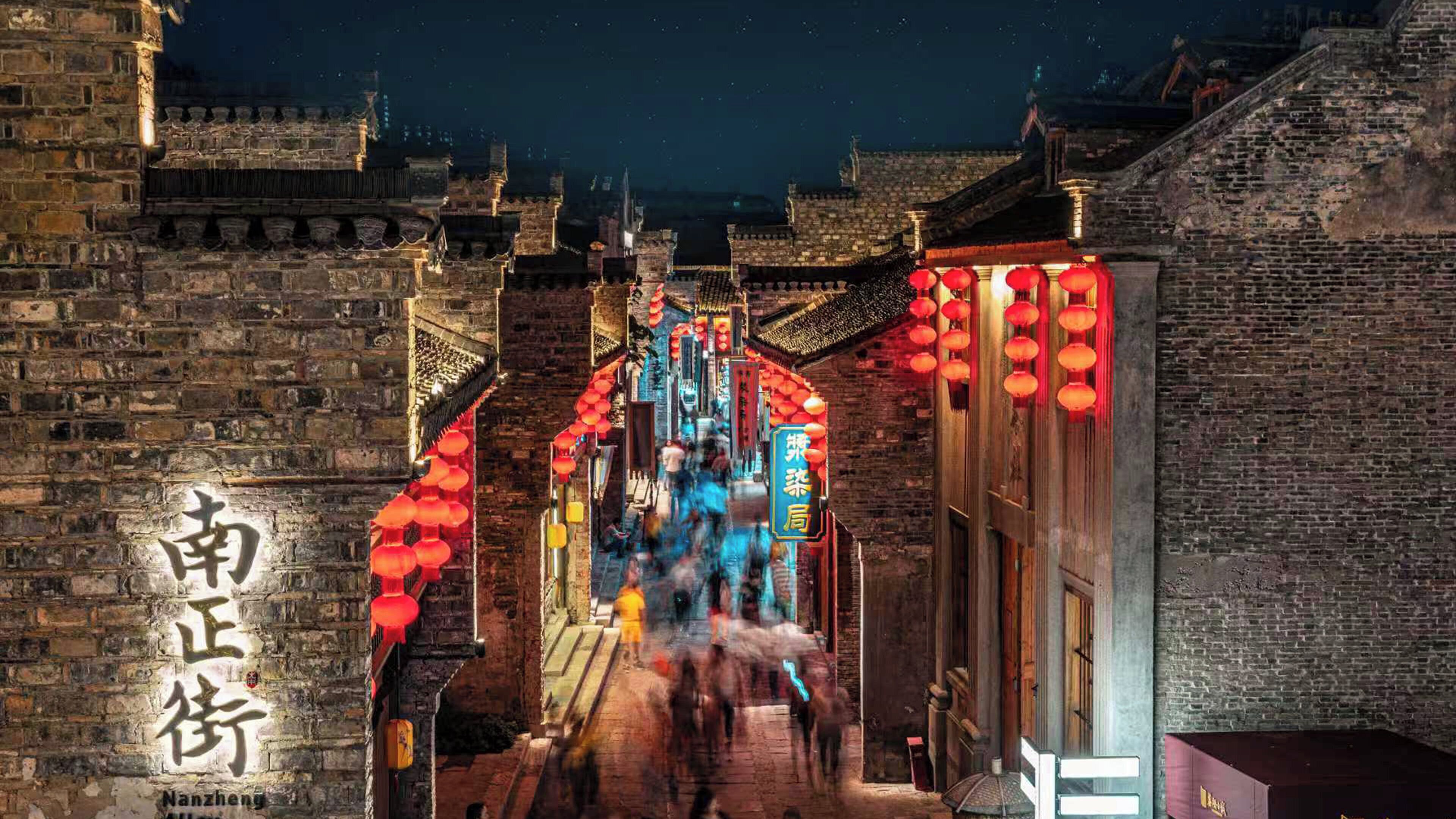 A narrow alleyway with traditional architecture, brick walls, and red lanterns.