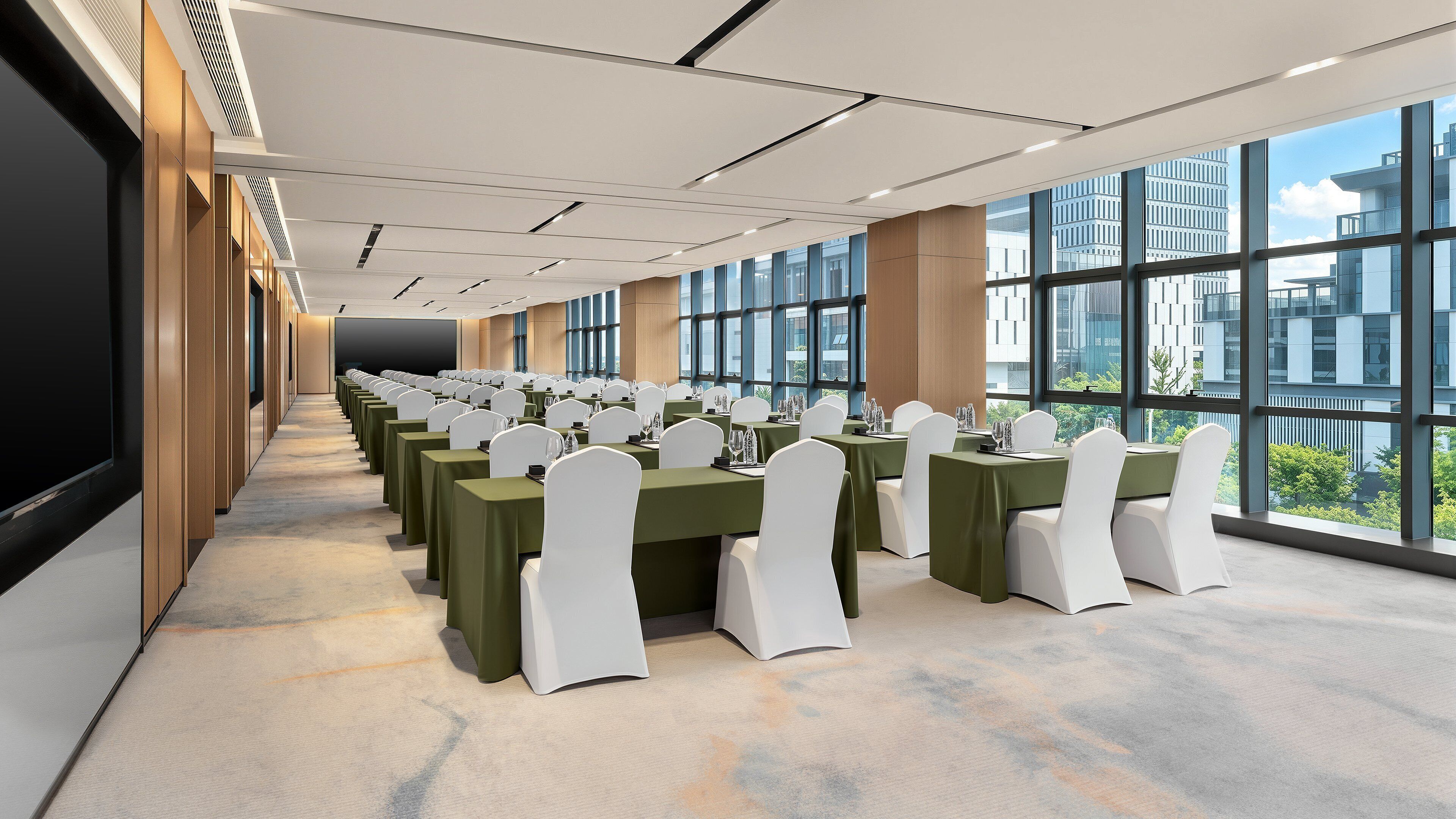 A conference room with rows of tables, chairs, and a large window offering a view of the cityscape.