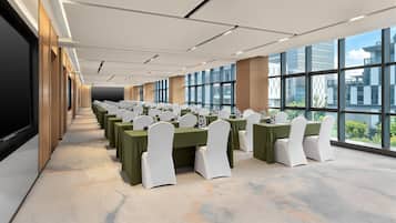 A conference room with rows of tables, chairs, and a large window offering a view of the cityscape.