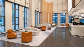 A spacious lobby with a reception desk, seating areas, and large windows.