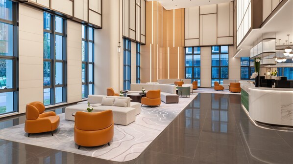 A spacious lobby with a reception desk, seating areas, and large windows.