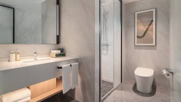 A modern bathroom with a marble sink, a glass-enclosed shower, and a toilet.