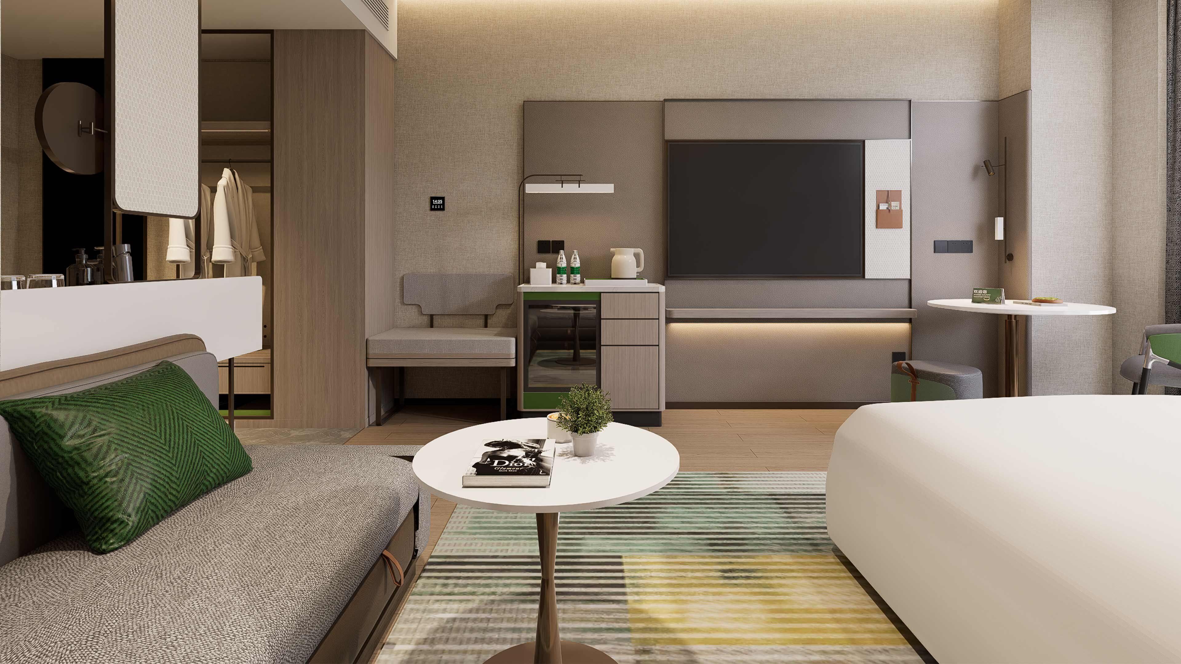 A modern hotel room with a sofa, a small round table, a bed, a kitchenette, and a large window.