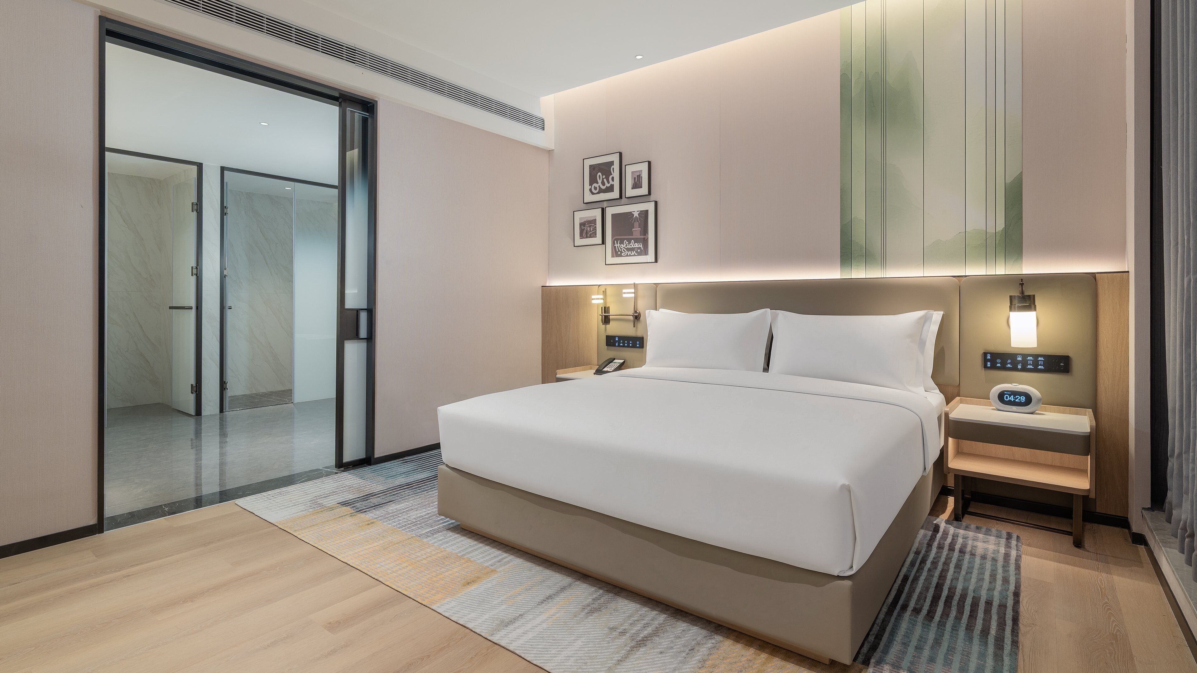 Quarto de hotel com uma cama grande, mesas de cabeceira, um criado-mudo, telefone fixado na parede e um relógio digital.