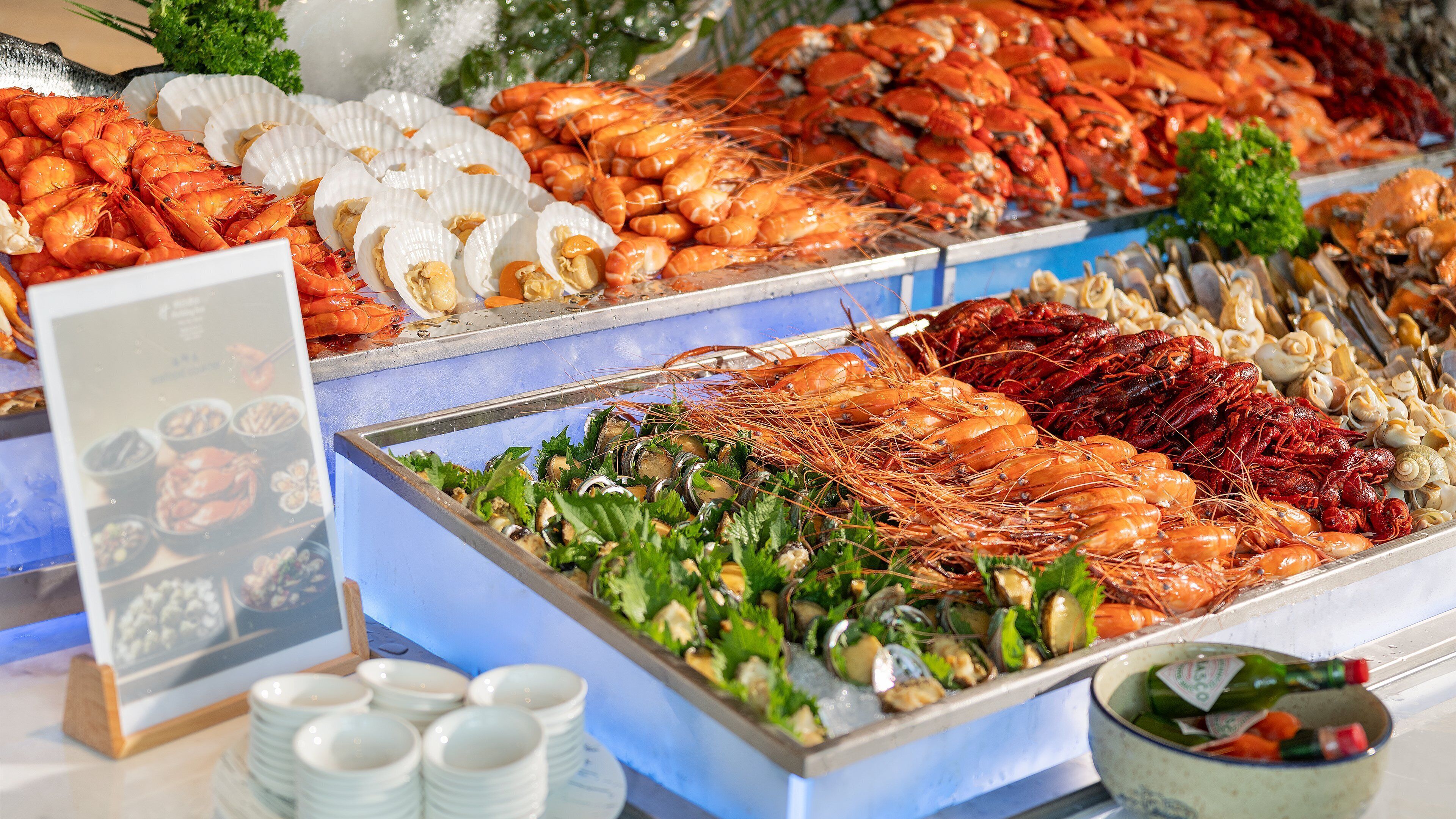 Exposição de frutos do mar, com diversos tipos de mariscos e camarões.