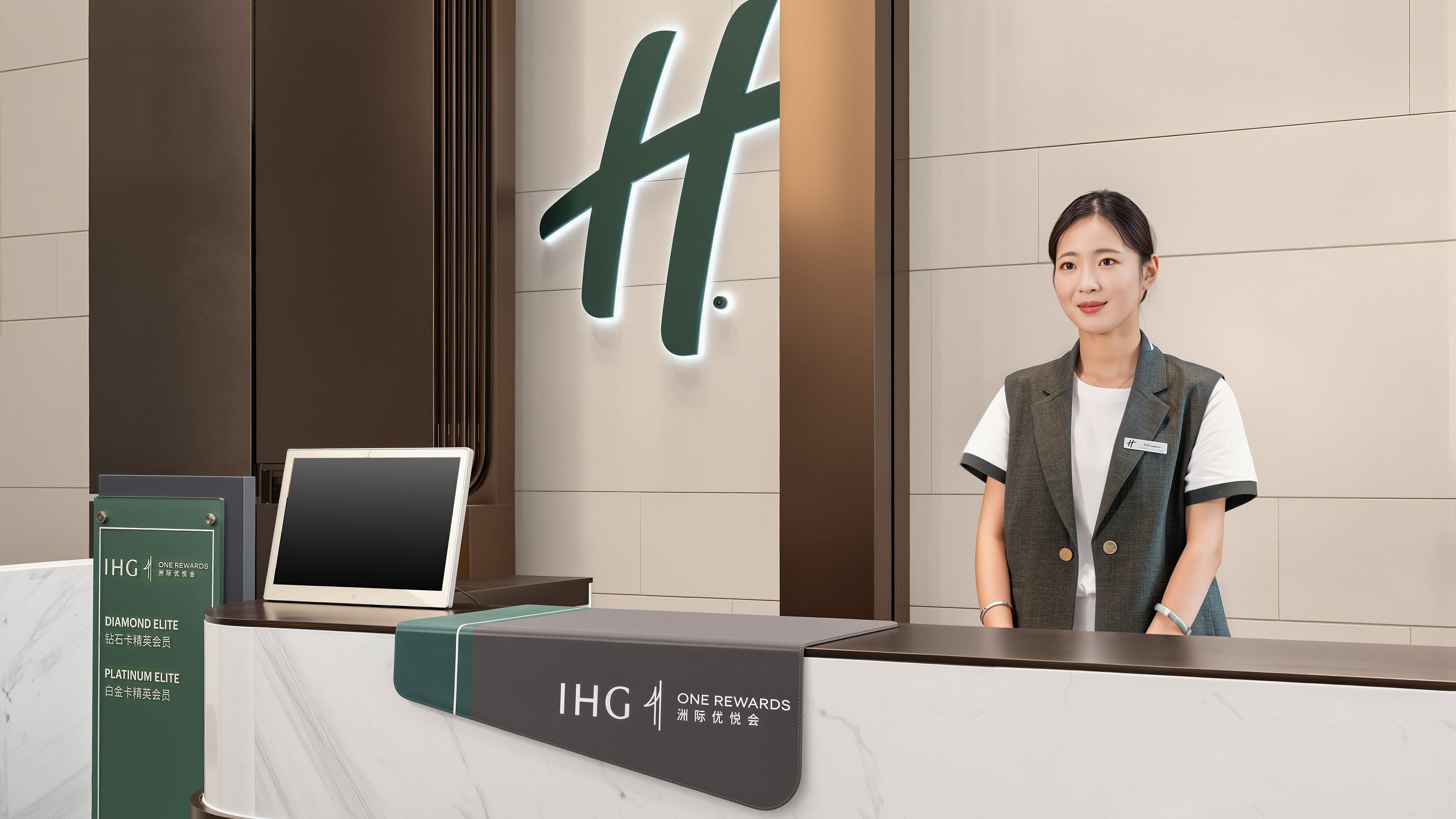 Un comptoir d’accueil équipé d’un ordinateur portable, d’une tablette et d’un panneau indiquant « IHG ONE REWARDS ».