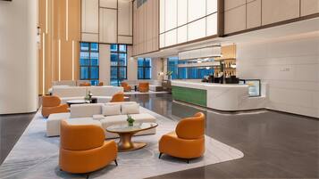 A spacious lobby with seating areas, a reception desk, and a bar.