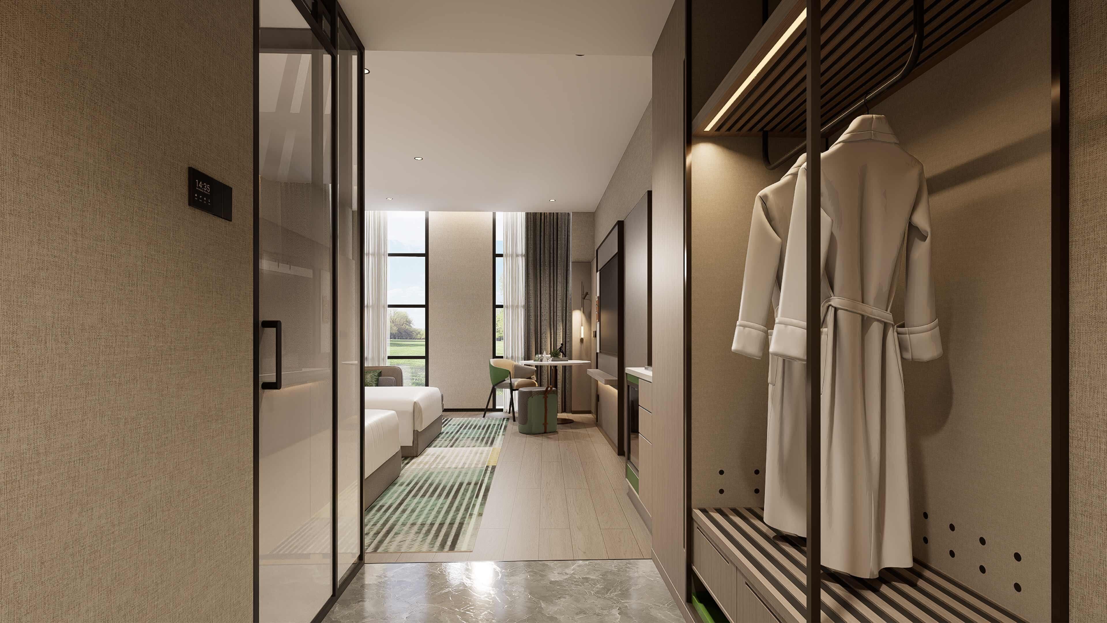 A modern hotel corridor with a bed, a small table, and a robe hanging on the wall.