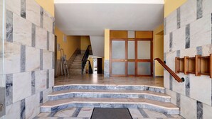 A staircase leading to a room with a door, a handrail, and a wall with a patterned tile design. - Apartment 'Fantástico T2 Albufeira Centro' with Sea View, Wi-Fi and Air Conditioning (Albufeira)