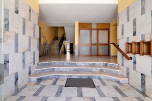 A staircase leading to a room with a door, a handrail, and a wall with a patterned tile design. - Apartment 'Fantástico T2 Albufeira Centro' with Sea View, Wi-Fi and Air Conditioning (Albufeira)