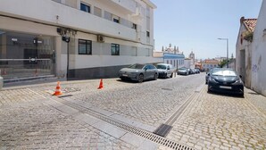 A cobblestone street with parked cars, a building with multiple floors, and a clear sky. - Apartment 'Fantástico T2 Albufeira Centro' with Sea View, Wi-Fi and Air Conditioning (Albufeira)