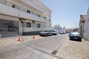 A cobblestone street with parked cars, a building with multiple floors, and a clear sky. - Apartment 'Fantástico T2 Albufeira Centro' with Sea View, Wi-Fi and Air Conditioning (Albufeira)