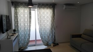 Ein modernes Wohnzimmer mit Sofa, Fernseher und Deckenventilator.