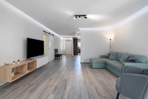 Ein modernes Wohnzimmer mit Flachbildfernseher, einer Couch, einem Couchtisch und einer Holzkonsole.